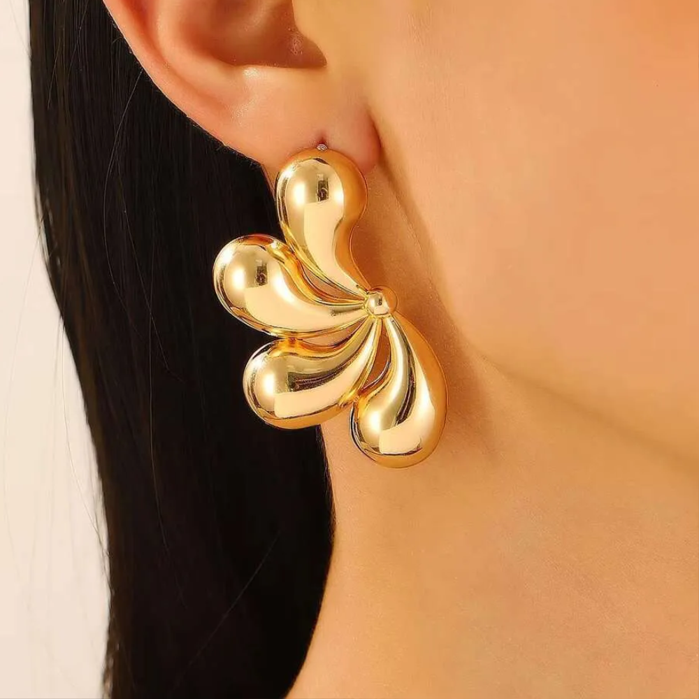 Gold flower statement earring worn on woman's ear