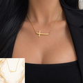 Gold-plated sideways cross necklace worn by a woman in a black outfit