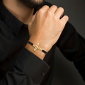 Open cross bracelet gold plated on black macramé cord worn on man's wrist