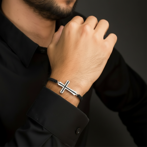 Black enamel cross bracelet silver on black macramé cord worn on man's wrist