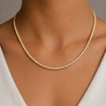 Gold tennis necklace on a woman's neck