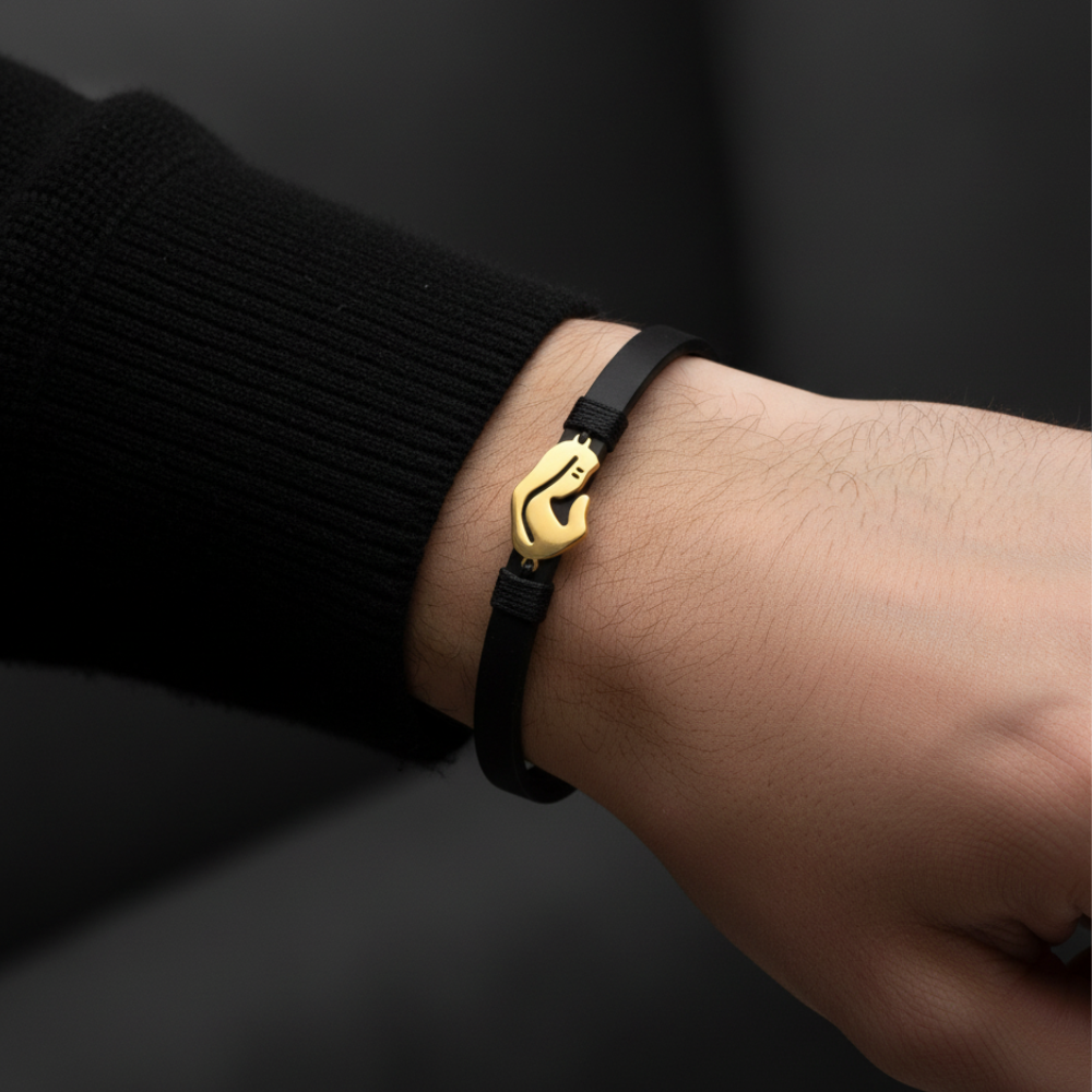 Black leather bracelet with gold mother and child charm worn on man's wrist